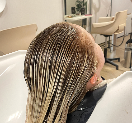 Freshly toned highlights being rinsed at the salon basin