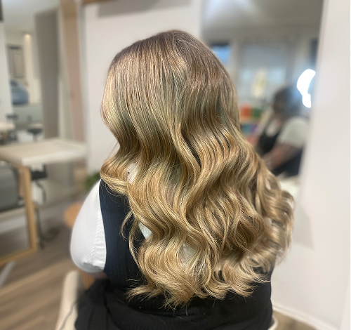 Blonde balayage hair styled in loose waves, back view